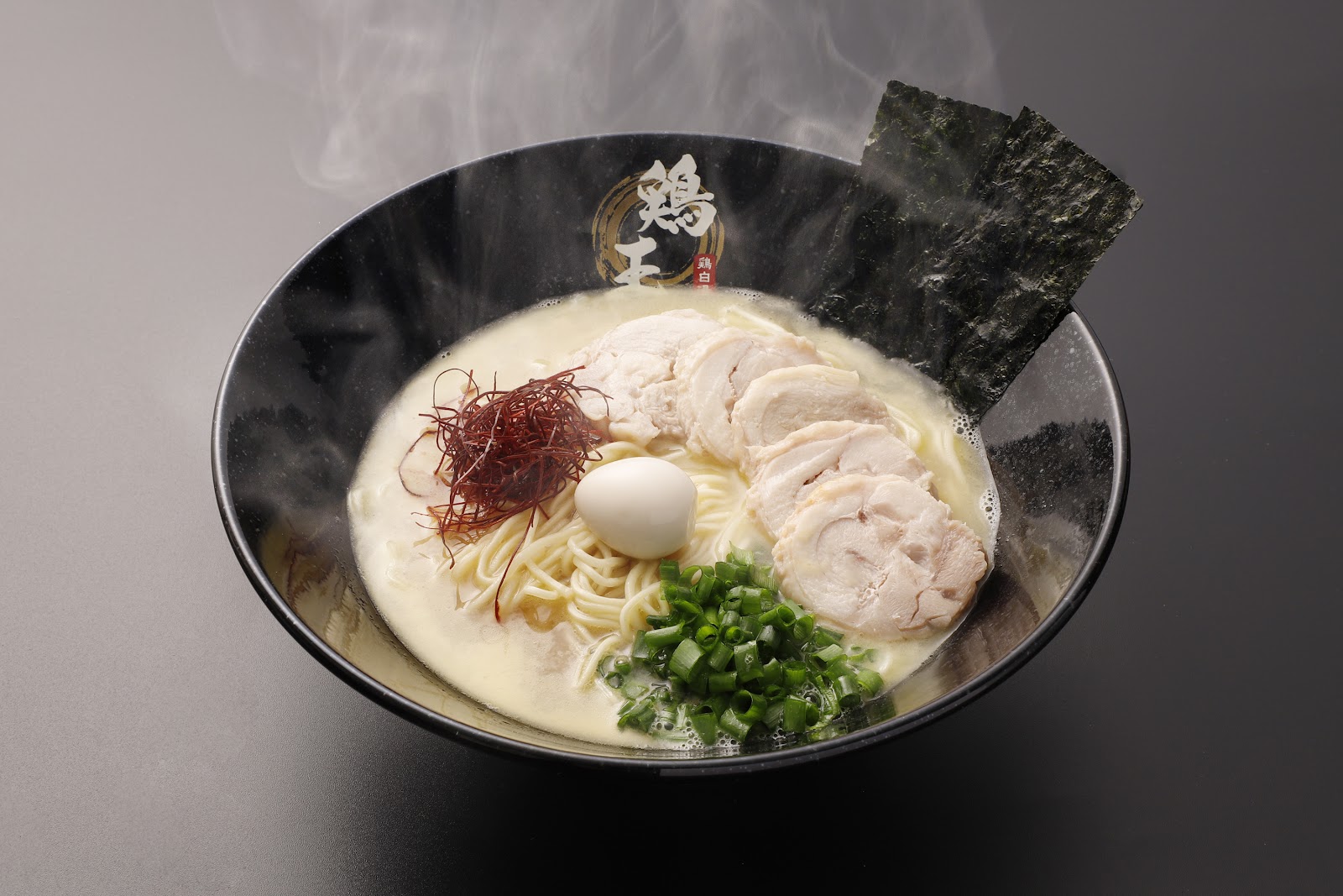 湯気が立つ黒い丼の鶏王子濃厚鶏白湯ラーメン